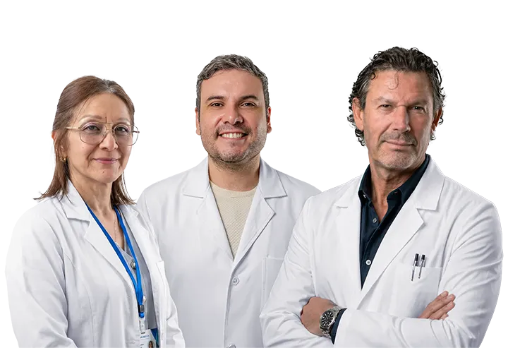 Three doctors in white coats standing together in a clinical setting, smiling at the camera.